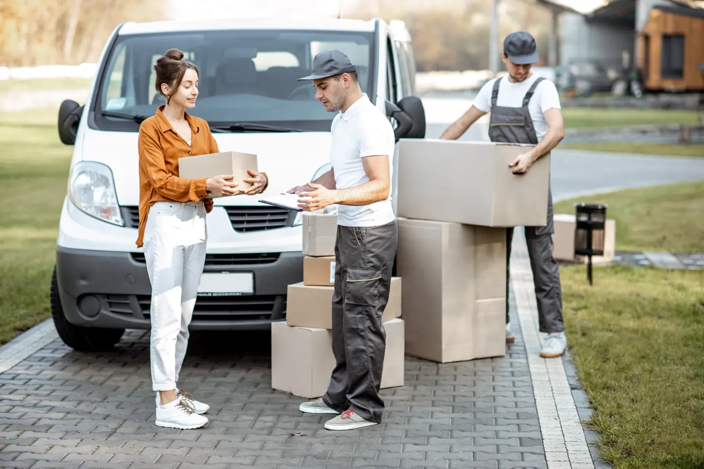 Movers handing boxes to a customer beside a van